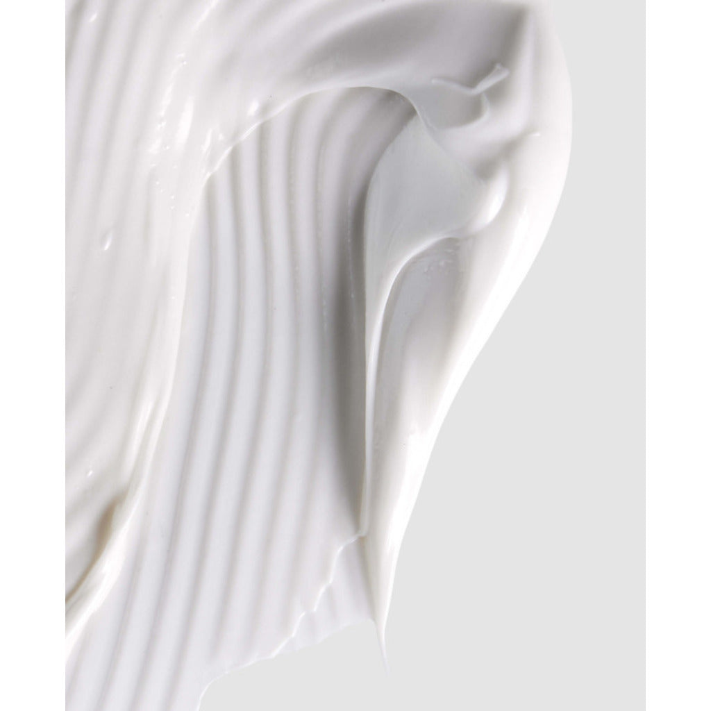 Close-up of white cream or paint with a smooth texture on a light gray background