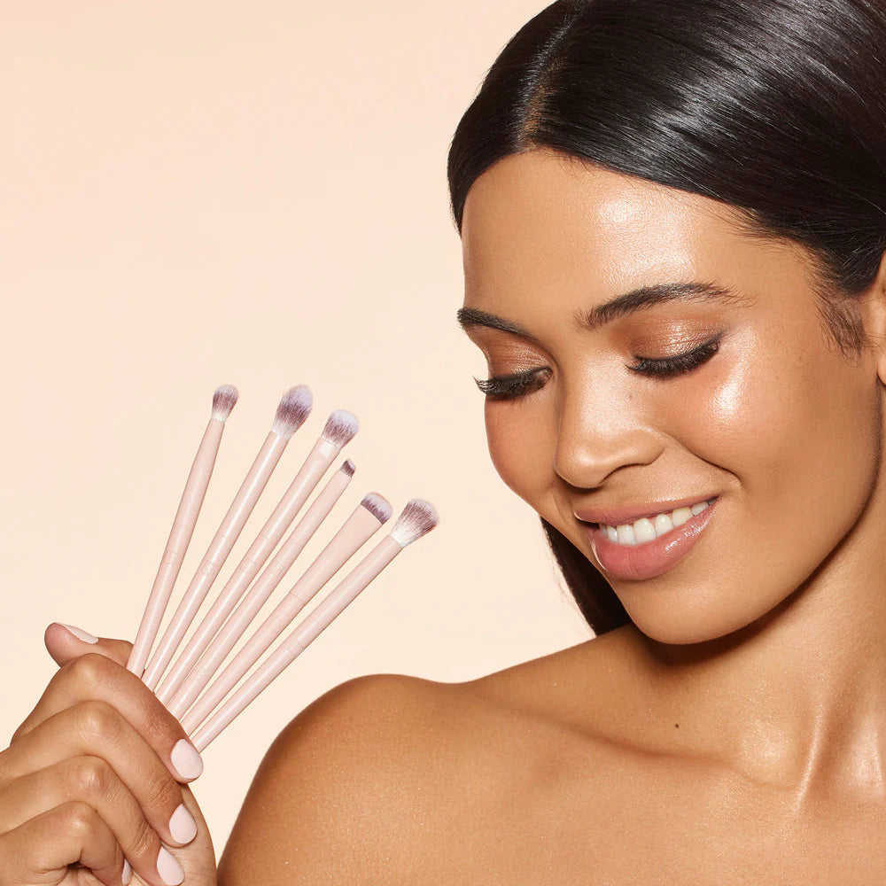 Woman holding makeup brushes with a beige background