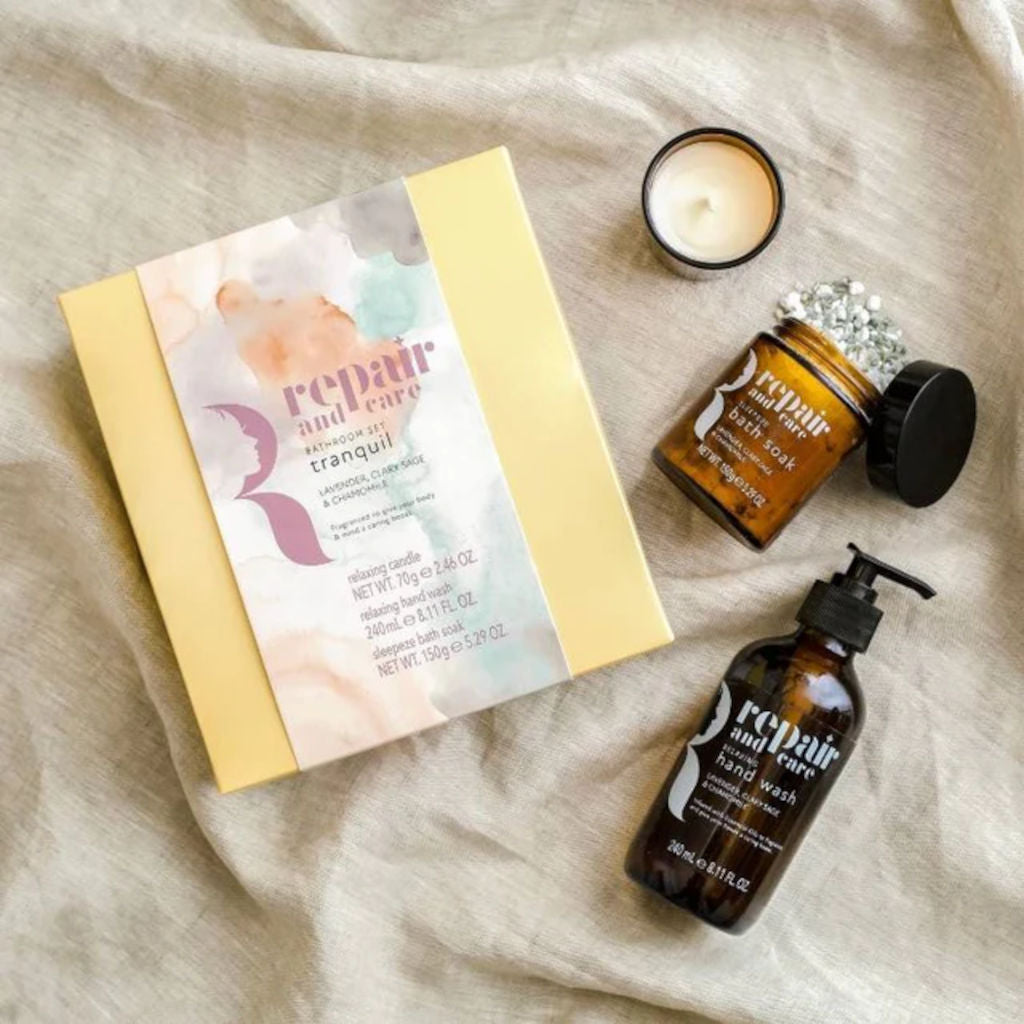 Cosmetic set with bottles, a box, and a candle on a textured surface