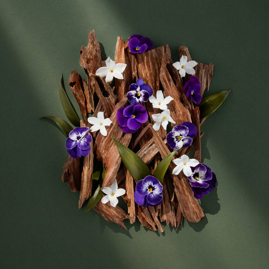 Decorative arrangement of purple and white flowers on wooden planks against a green background