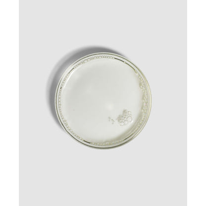 Round ceramic plate with decorative edge on a light gray background