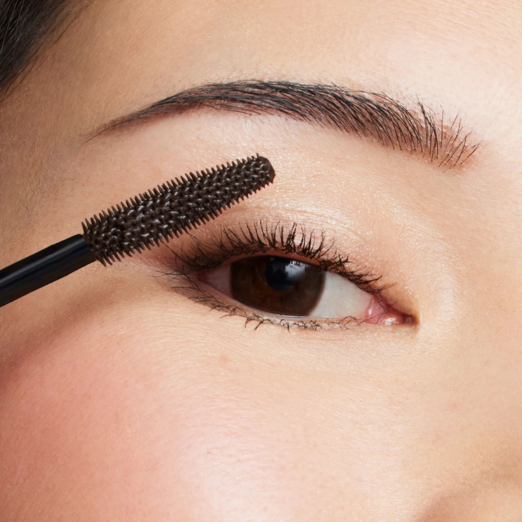Person applying mascara to their eyelashes with a close-up view.