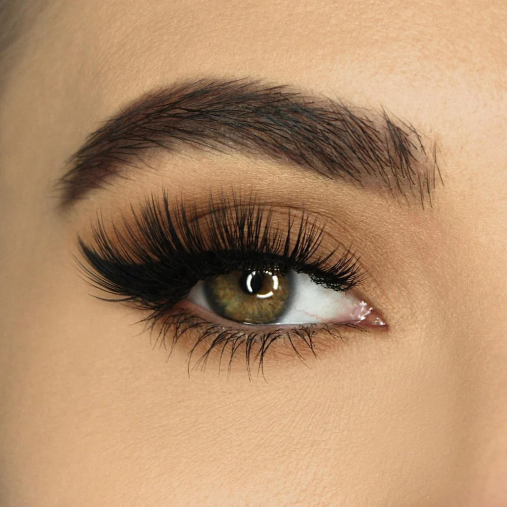 Close-up of a person's eye with long, dark eyelashes and brown irises.