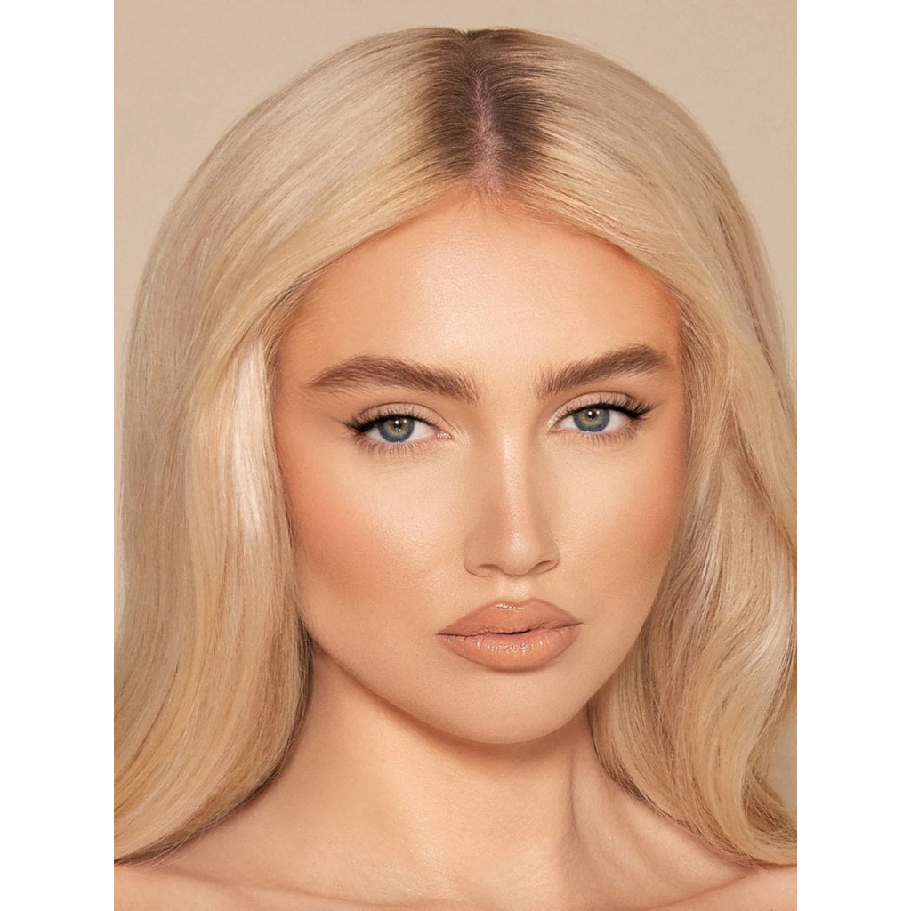 Close-up of a person with blonde hair and makeup on a beige background