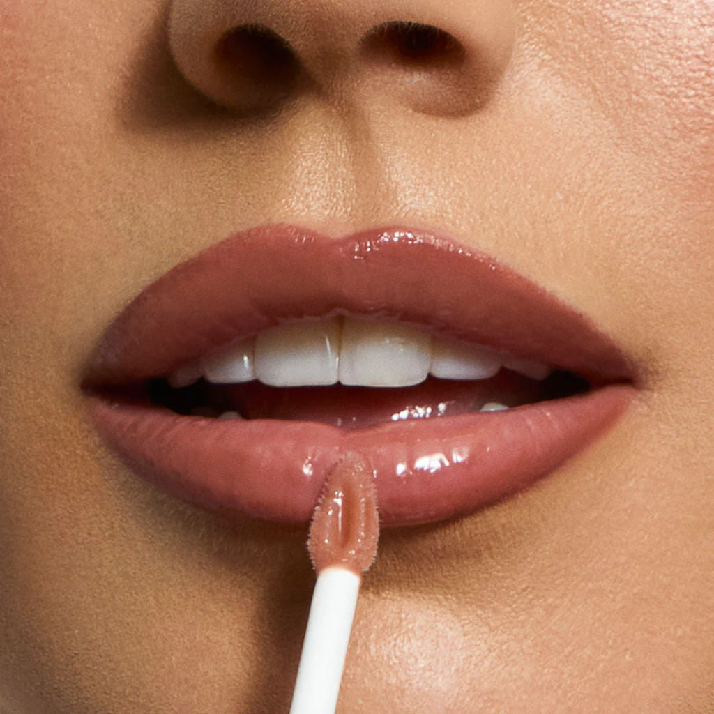 Close-up of a person applying lip gloss with a applicator.