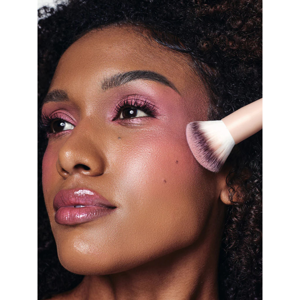 Woman applying makeup with a brush to her face