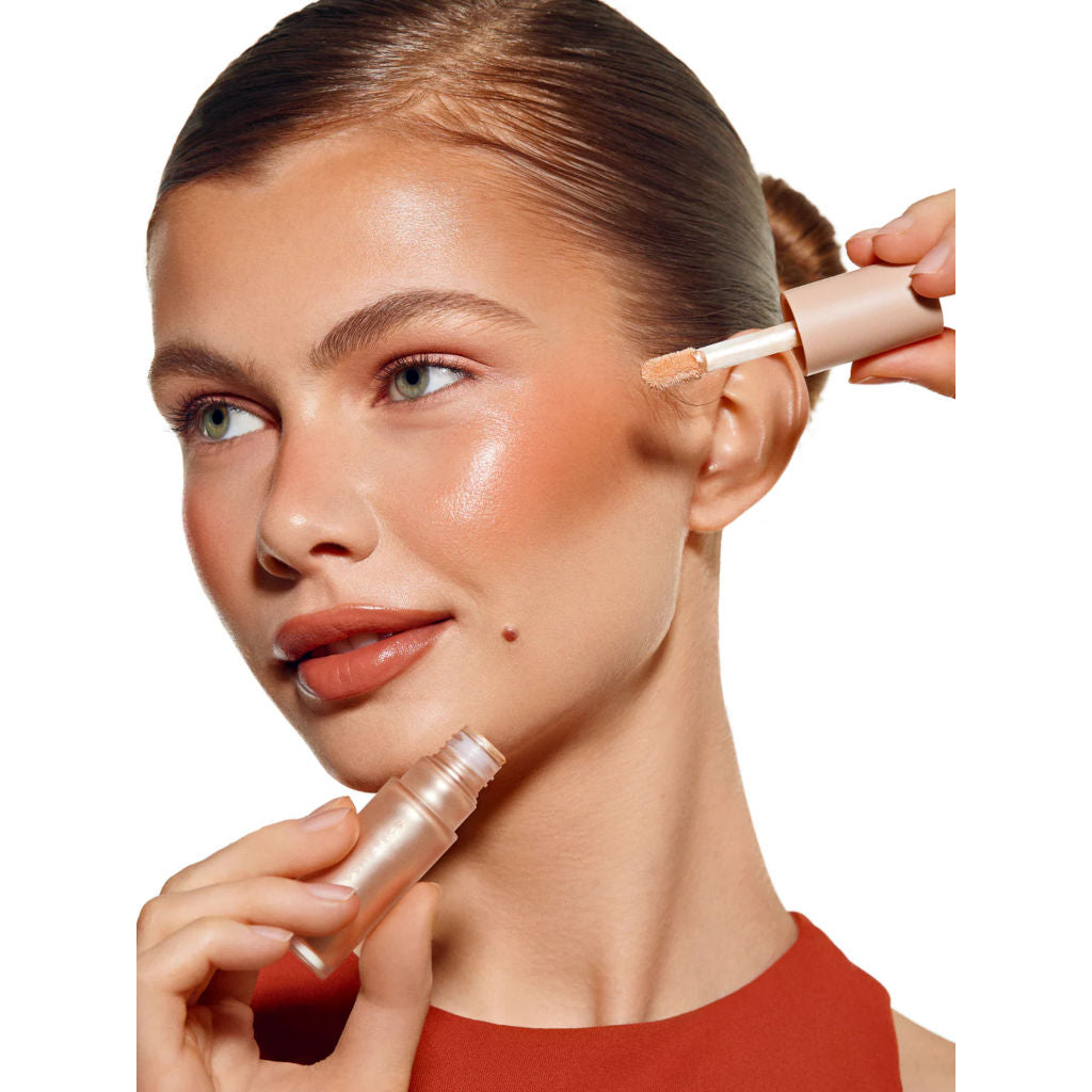 Woman applying makeup with a brush to her face on a white background