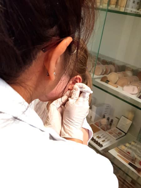 image showing pharmacist piercing ear of young child